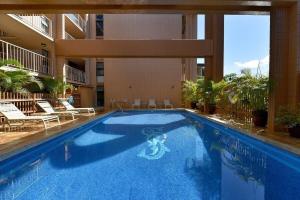 a swimming pool in a hotel with chairs and a building at Kaleialoha 401 · KA 401 Spacious Studio w Mountain View Pool AC in Kahana