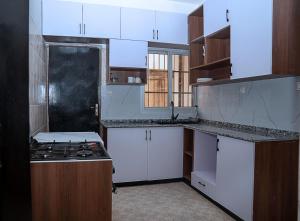 a kitchen with white cabinets and a stove top oven at MICASO Guest House in Limbe