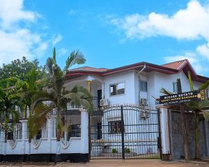 a white house with a gate and palm trees at MICASO Guest House in Limbe