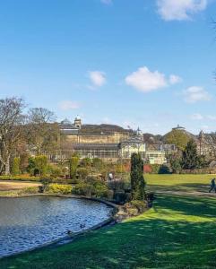 a pond in a park with buildings in the background at Pavilion Mews Luxury Apartment in Buxton