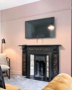 a living room with a fireplace with a flat screen tv above it at Pavilion Mews Luxury Apartment in Buxton