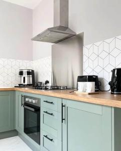 a kitchen with white cabinets and a stove top oven at Pavilion Mews Luxury Apartment in Buxton +2 photos