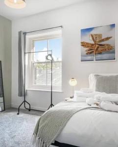 a white bedroom with a bed and a window at Pavilion Mews Luxury Apartment in Buxton