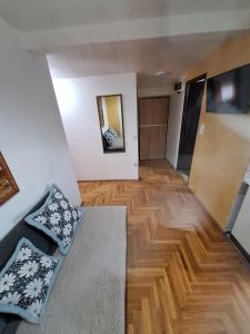 Una sala de estar con un sofá y suelo de madera. en Rooms3, en Beograd