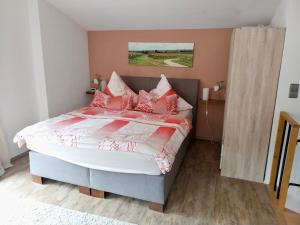 Un dormitorio con una cama con almohadas rojas y blancas. en Ferienwohnung Familie Westermann, en Kapellen-Drusweiler