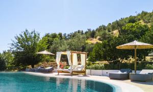 einen Pool mit Stühlen und Sonnenschirmen neben einem Pool in der Unterkunft Skiathos Country Studios in Skiathos-Stadt