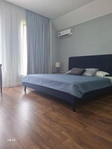 a bedroom with a large bed in a room with wooden floors at Tsitadel in Zugdidi +6 photos