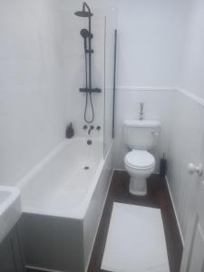 a white bathroom with a toilet and a bath tub at Clubhouse, North End, Bedale DL8 1AB in Bedale