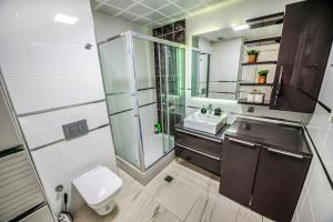 a bathroom with a shower and a toilet and a sink at Sky-High 1BR 30 Floor Spa,Gym Cevahir Tower A in Skopje +20 photos