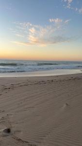 einen Strand mit Fußabdrücken im Sand und im Ozean in der Unterkunft Salt & Sand Stay in Singleton