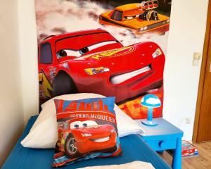 een slaapkamer met een bed met een muurschildering van Disney-auto's bij Garden-Apartment next to the forest, free parking in Schonach +34 foto's