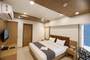 a bedroom with a large bed and a tv at Hotel The Tulip in Diu