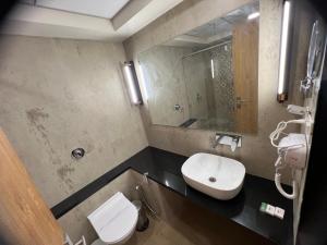 a bathroom with a sink and a toilet and a mirror at Hotel The Tulip in Diu +6 photos