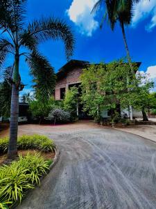 a building with a palm tree in front of it at Monkey Garden Hotel in Polonnaruwa