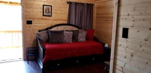 a bedroom with a bed with a red blanket at Texas State Glamping in this Charming Cabin Rental for Six in Pipe Creek in Pipe Creek +17 photos