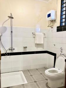 a bathroom with a toilet and a towel dispenser at The Secret Garden Hotel Moshi in Moshi