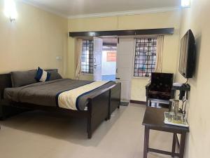 a bedroom with a bed and a television and a table at Bruton resorts in Kodaikānāl