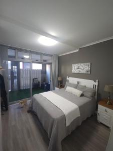 een slaapkamer met een groot bed en een groot raam bij Seaside Charm in Bloubergstrand