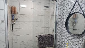 een badkamer met een douche en een spiegel bij Seaside Charm in Bloubergstrand
