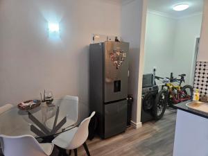 een keuken met een roestvrijstalen koelkast en een tafel en stoelen bij Seaside Charm in Bloubergstrand +6 foto's