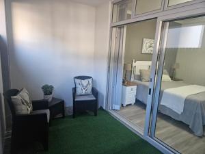 een slaapkamer met een bed, een spiegel en een stoel bij Seaside Charm in Bloubergstrand