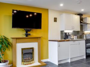uma cozinha com lareira e uma TV de tela plana na parede em Dutch Barn One - Uk12872 em Brynkir