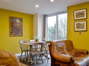 uma sala de estar com uma mesa e uma cadeira em Dutch Barn One - Uk12872 em Brynkir
