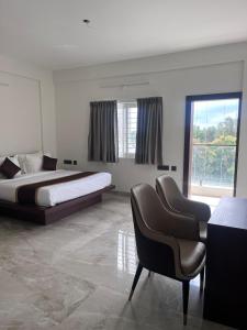 a bedroom with two beds and a chair in it at Hotel The Novelty in Kānpur