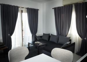 een woonkamer met een zwarte bank en 2 stoelen bij Dea Aureum Apartment Limassol in Limassol