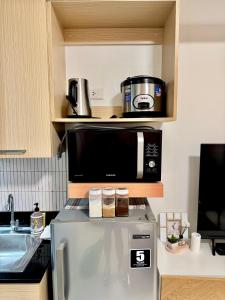 a microwave sitting on top of a refrigerator in a kitchen at Suite Escapes Brenthill Baguio 1 Bedroom in Baguio