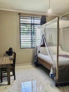 a bedroom with a bed and a table and a window at The Secret Garden Hotel Moshi in Moshi