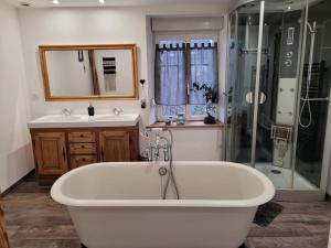 a bathroom with a tub and a shower and a sink at Gîte cosy dans les Vosges in Rochesson +9 photos