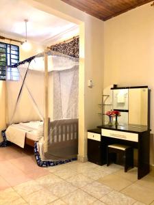 a bedroom with a bed and a desk and a mirror at The Secret Garden Hotel Moshi in Moshi +8 photos