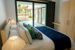a bedroom with a bed with pillows and a window at Villa Serenity Seafront with Tropical Gardens by Serenity in Calodyne