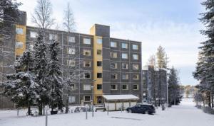 a building in the snow with a car parked in front at Winter Moon Aparment in Rovaniemi