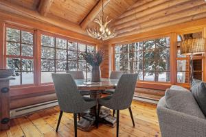 Un comedor con mesa y sillas y ventanas. en RMR: Teton View Cabin Home in WilsonWY, en Wilson