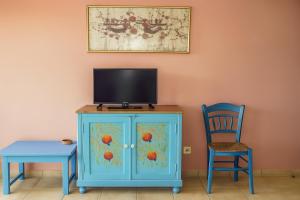 KástronにあるPolytropon Apartmentsのテレビとテーブルと椅子が置かれた青いキャビネット