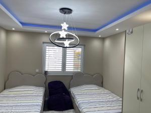 コソフスカ・ミトロビツァにあるLuxury Homeのベッド2台とシャンデリアのある寝室