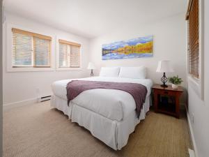Un dormitorio blanco con una cama grande y dos ventanas. en RMR: Sleeping Indian West 4 Condo in Teton Village, en Teton Village