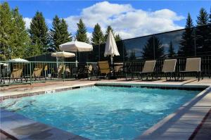 Una piscina con sillas y sombrillas al lado en RMR: Sleeping Indian West 4 Condo in Teton Village, en Teton Village