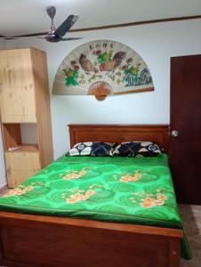 a bedroom with a bed with a green comforter at Villa Onus in Aluthgama