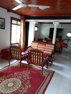 a room with wooden chairs and a red rug at Villa Onus in Aluthgama