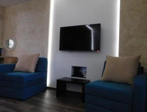 a living room with two blue chairs and a flat screen tv at Apartman broj 19 in Banja Koviljača