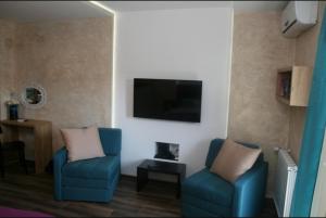 a living room with two blue chairs and a flat screen tv at Apartman broj 19 in Banja Koviljača