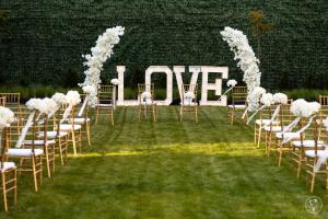 a wedding aisle with white chairs and a large love sign at Moment in Strzelce Opolskie