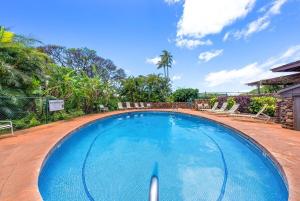 a large blue swimming pool with chairs and trees at Kaanapali Plantation 34 · KPL 34 2BD Pool & Resort's Amenities, in Kahana