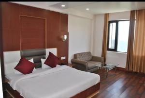 a hotel room with a large bed and a chair at Hotel Natraj International in Patnitop