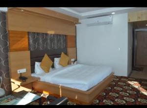 a bedroom with a large bed with a wooden headboard at Hotel Natraj International in Patnitop +3 photos