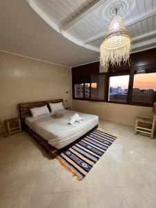 una camera da letto con un letto grande e un lampadario di Waves House Tamraght - Surf & Chill Hostel a Tamraght Ouzdar
