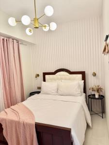 ein Schlafzimmer mit einem Bett mit weißen Laken und einem Kronleuchter in der Unterkunft Suite Escapes at Brenthill Baguio with Balcony in Baguio City